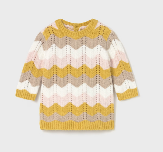 Mayoral Baby Girl Autumn Wave Knitted Dress — front ghost flat-lay on light grey background; full-length view of a baby knitted dress in an all-over chevron wave knit pattern in mustard yellow, pale pink, soft taupe and cream; ruffled crew neckline with mustard yellow ribbed trim; long sleeves with mustard yellow ribbed cuffs; mustard yellow ribbed hem band at the bottom; textured wave knit stitch visible throughout the body; light grey background; demonstrates the front silhouette, neckline detail and full