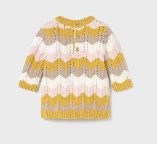 Mayoral Baby Girl Autumn Wave Knitted Dress — back ghost flat-lay on light grey background; full-length rear view of a baby knitted dress in an all-over chevron wave knit pattern in mustard yellow, pale pink, soft taupe and cream; ruffled crew neckline with mustard yellow ribbed trim visible at the top; two small mustard-toned buttons on the back placket at the neckline for easy dressing; long sleeves with mustard yellow ribbed cuffs; mustard yellow ribbed hem band at the bottom; textured wave knit stitch v