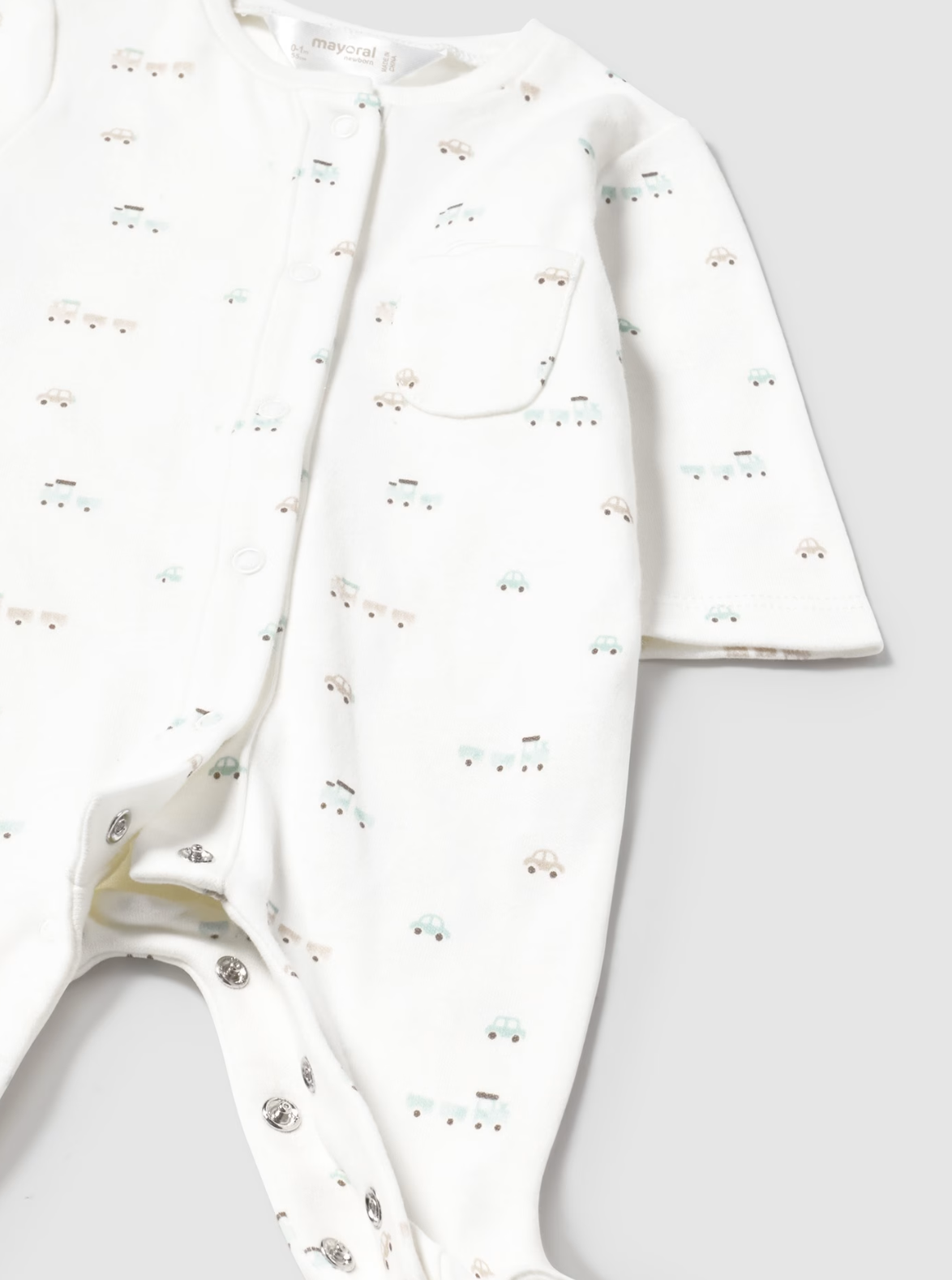 White baby outfit with subtle NEUTRAL TRAIN pattern 