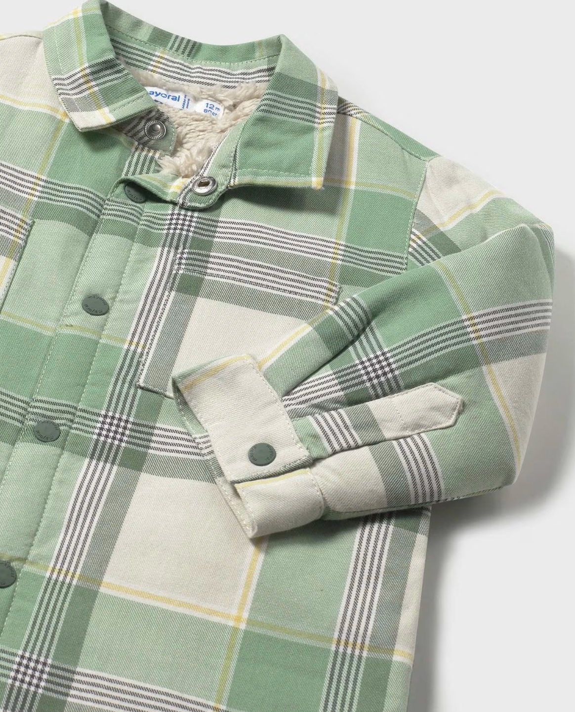 Close-up — sherpa fleece lining at collar; snap poppers; cuff popper; plaid weave texture. 