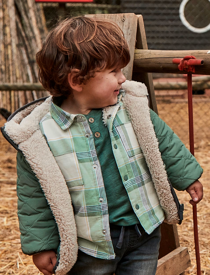 Lifestyle — toddler boy on farm, layered outfit, overshirt worn open over ribbed knit. 