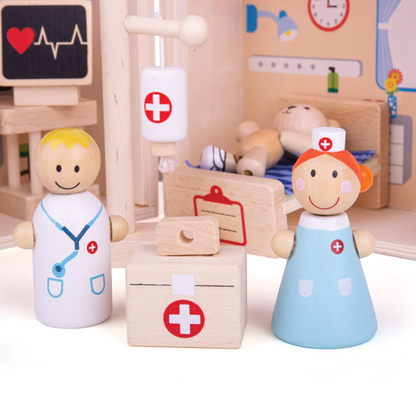Wooden toy doctor and nurse figures with medical accessories in a playroom setting. MINI WOODEN HOSPITAL PLAYSET | BIGJIGS
