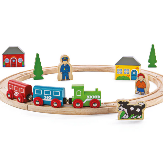 A wooden train set with a circular track and includes one engine, two carriages, and various track accessories such as houses, trees, and figures. The set is brightly colored and made from wood. MY FIRST TRAIN SET | BIGJIGS