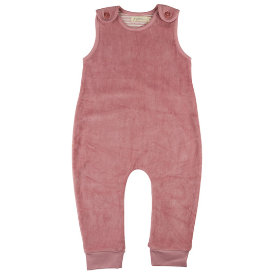 Pigeon Organics Organic Cotton Velour Baby Playsuit in Pink — front ghost flat-lay on white background; dusty rose/antique pink 100% GOTS certified organic cotton velour sleeveless playsuit; round/crew neckline with soft cream and white striped jersey lining visible at the inner neckline edge; two small round self-covered dark rose/burgundy snap buttons on each shoulder tab at the neckline — four snap buttons in total — for easy over-the-head dressing; velour outer with a beautiful soft plush pile texture c