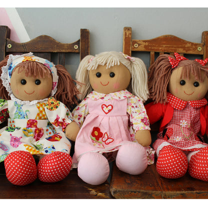 Three dolls in colorful dresses sitting on a wooden bench. PINK GINGHAM WITH BUNCHES AND APRON RAGDOLL | POWELL CRAFT