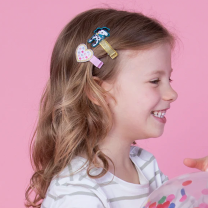 Child with colorful hair clips on a pink background. RACHEL ELLEN HAIR CLIPS - DOGS