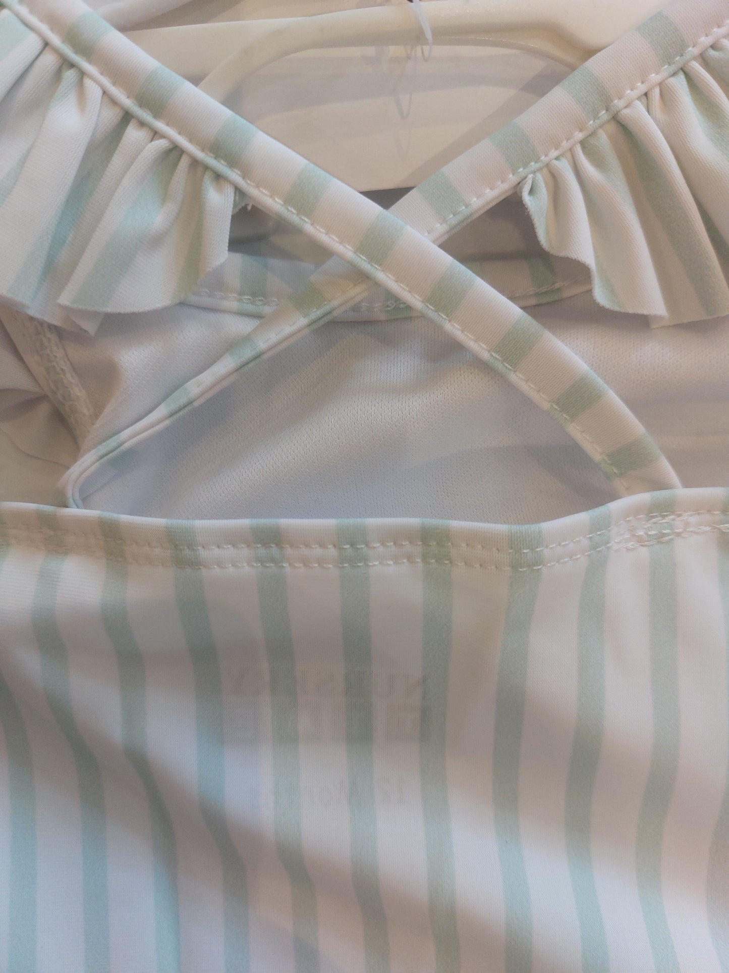 Close-up of a striped fabric with green and beige colors. RUFFLE SWIMSUIT WITH SUNGLASSES SET- MINT STRIPE | NURSERY TIME