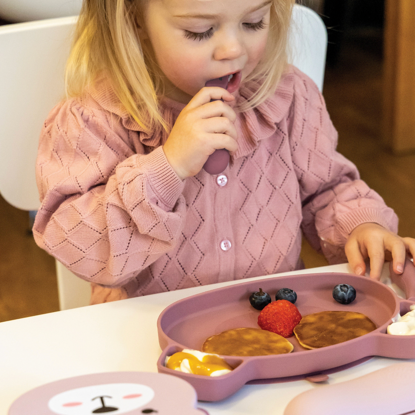 Child eating pancakes with fruit on a pink tray. SILICONE BABY TRAVEL CUTLERY SET WITH CASE - 2 COLOURS | TUM TUM