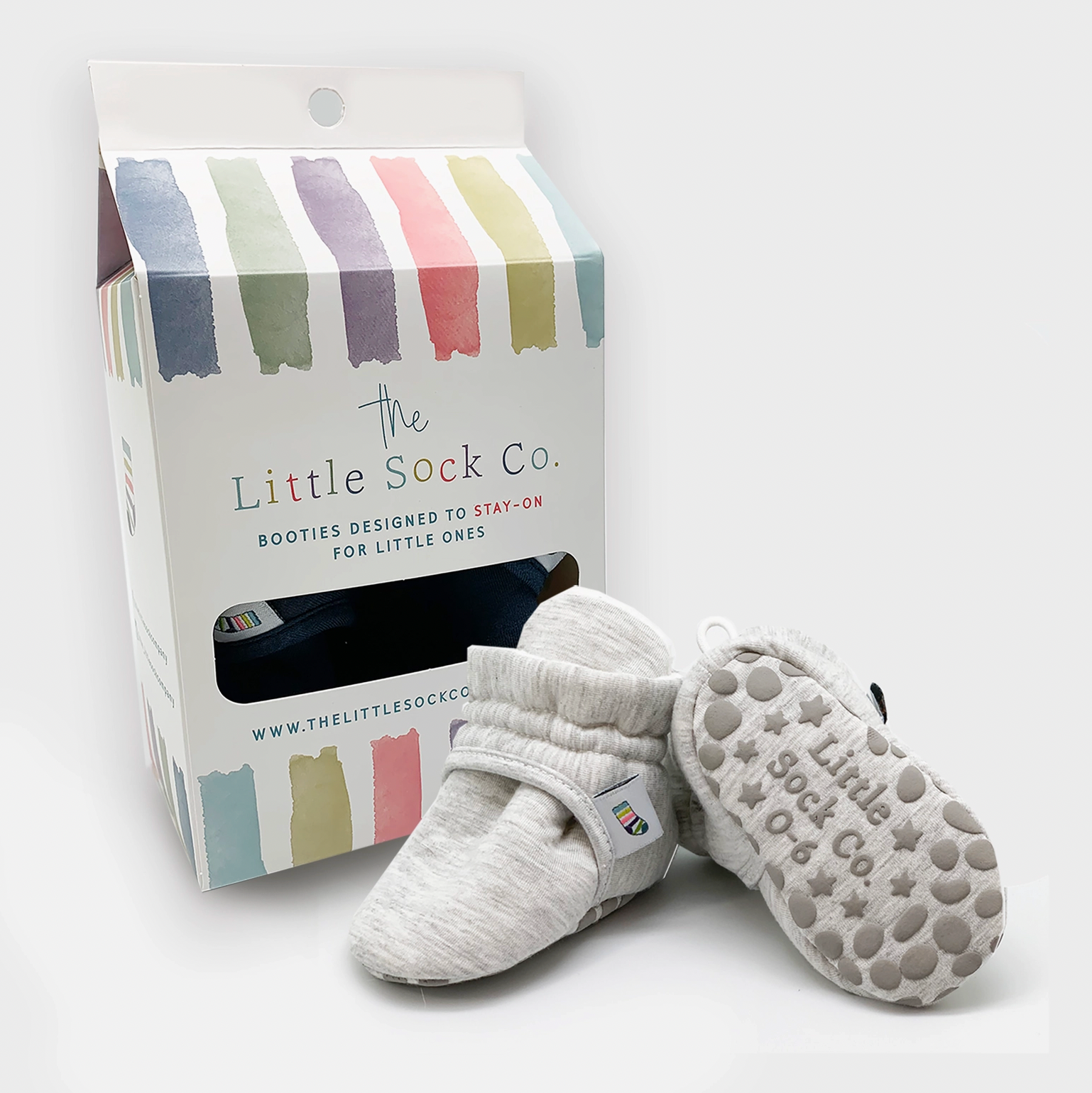 Gray baby booties with textured soles next to a 'The Little Sock Co.' packaging box on a white background. STAY-ON, NON-SLIP BOOTIE - GREY | THE LITTLE SOCK CO.