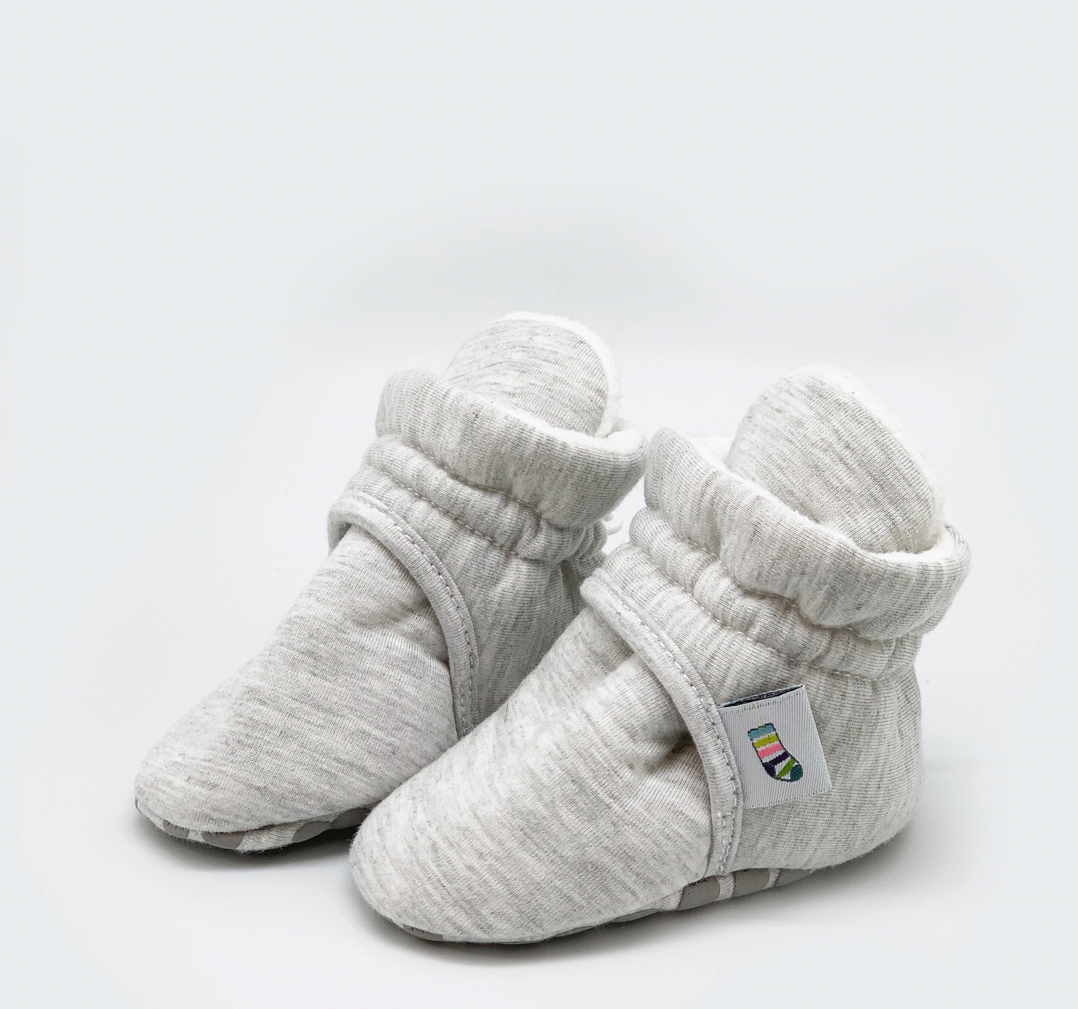 Pair of gray baby booties on a light gray background