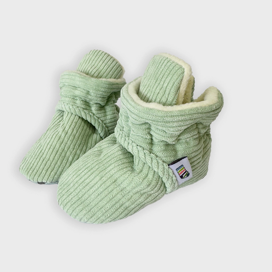 Pair of green baby booties with a textured pattern on a white background STAY-ON, NON-SLIP BOOTIE - PISTACHIO CORDUROY | THE LITTLE SOCK CO.