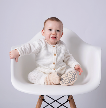 Baby in a white knit outfit sitting on a white chair with a plain background STAY-ON, NON-SLIP BOOTIE - SHERPA | THE LITTLE SOCK CO.