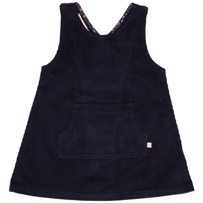 A sleeveless dark navy corduroy pinafore dress with a front patch pocket and a small white brand tag on the lower right hem, shown against a plain white background.