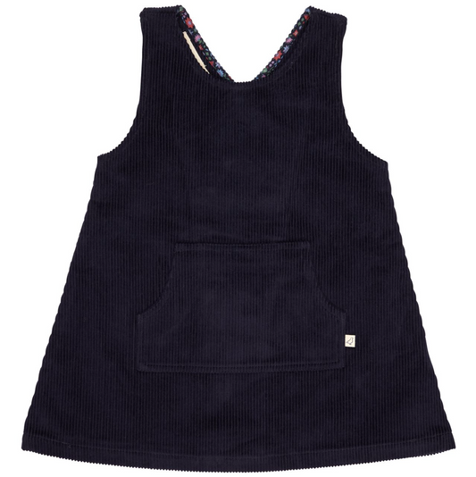 A sleeveless dark navy corduroy pinafore dress with a front patch pocket and a small white brand tag on the lower right hem, shown against a plain white background.