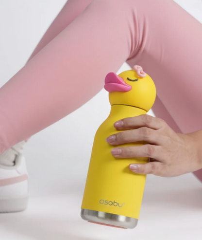 A person in pink leggings holds a yellow duck-shaped water bottle with a pink lid and a stainless steel base. The brand name 'asobu' is printed near the bottom of the bottle.