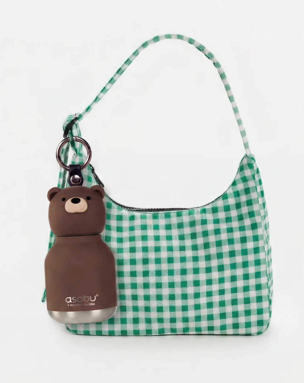 Green and white gingham check shoulder bag with a brown bear-shaped bottle charm attached via a key ring, shown on a plain white background.