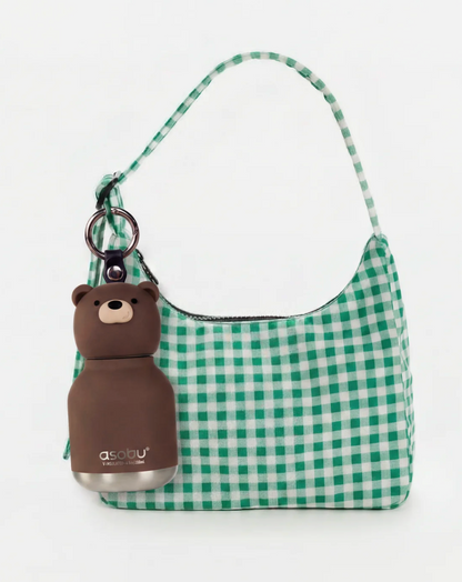 Green and white gingham check shoulder bag with a brown bear-shaped bottle charm attached via a key ring, shown on a plain white background.