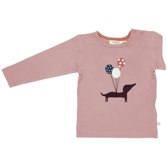 Pigeon Organics pink long sleeve children's t-shirt with a sausage dog holding polka dot balloons placement print on the front and shoulder poppers