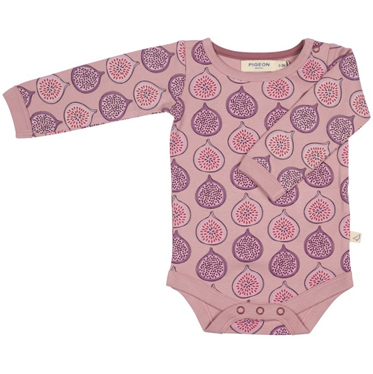 A long-sleeve baby bodysuit by Pigeon in a dusty mauve pink color, featuring an all-over print of purple and pink figs. The bodysuit has three snap buttons at the crotch and a small fabric brand tag on the right side.