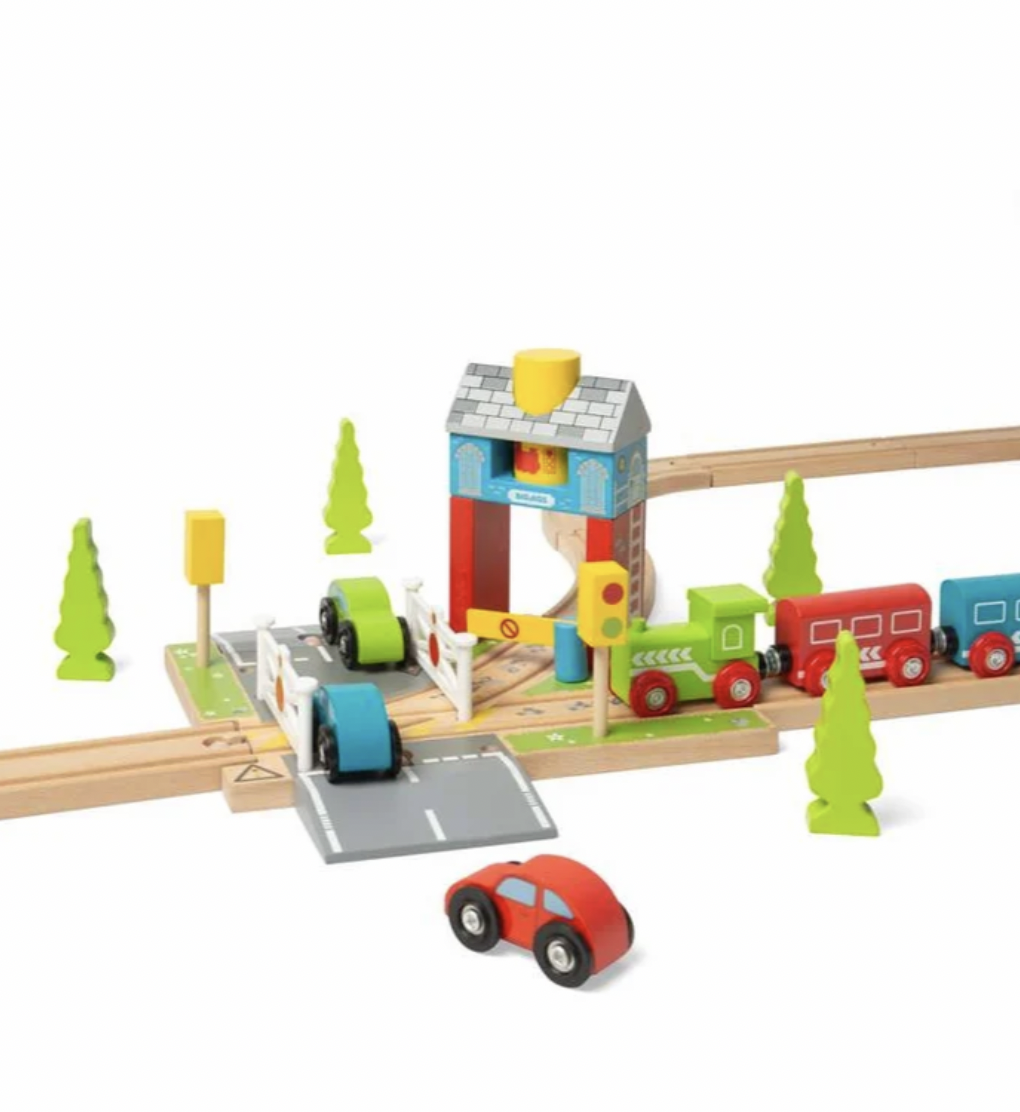 A wooden toy train set with a small train, tracks, a station platform, signal posts, trees, and a separate red car on a white background.