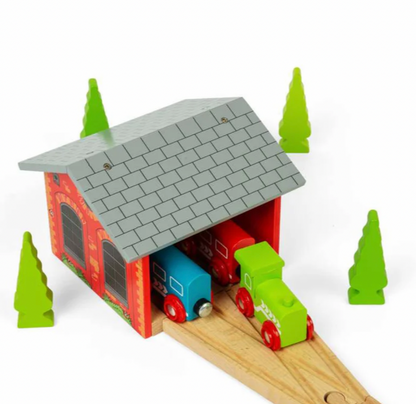 A wooden toy train garage set with a red and orange garage house, gray roof, light wood tracks, colorful toy trains, and green tree shapes on a white background.