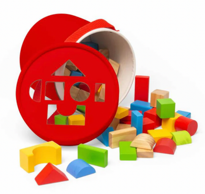 A red wooden shape-sorting toy bucket with colorful wooden blocks spilling out onto a white background.