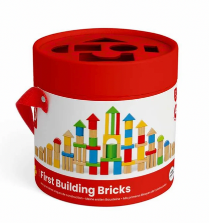 A red cylindrical storage container for wooden building blocks, featuring a white label with colorful toy bricks and the text 'First Building Bricks'.