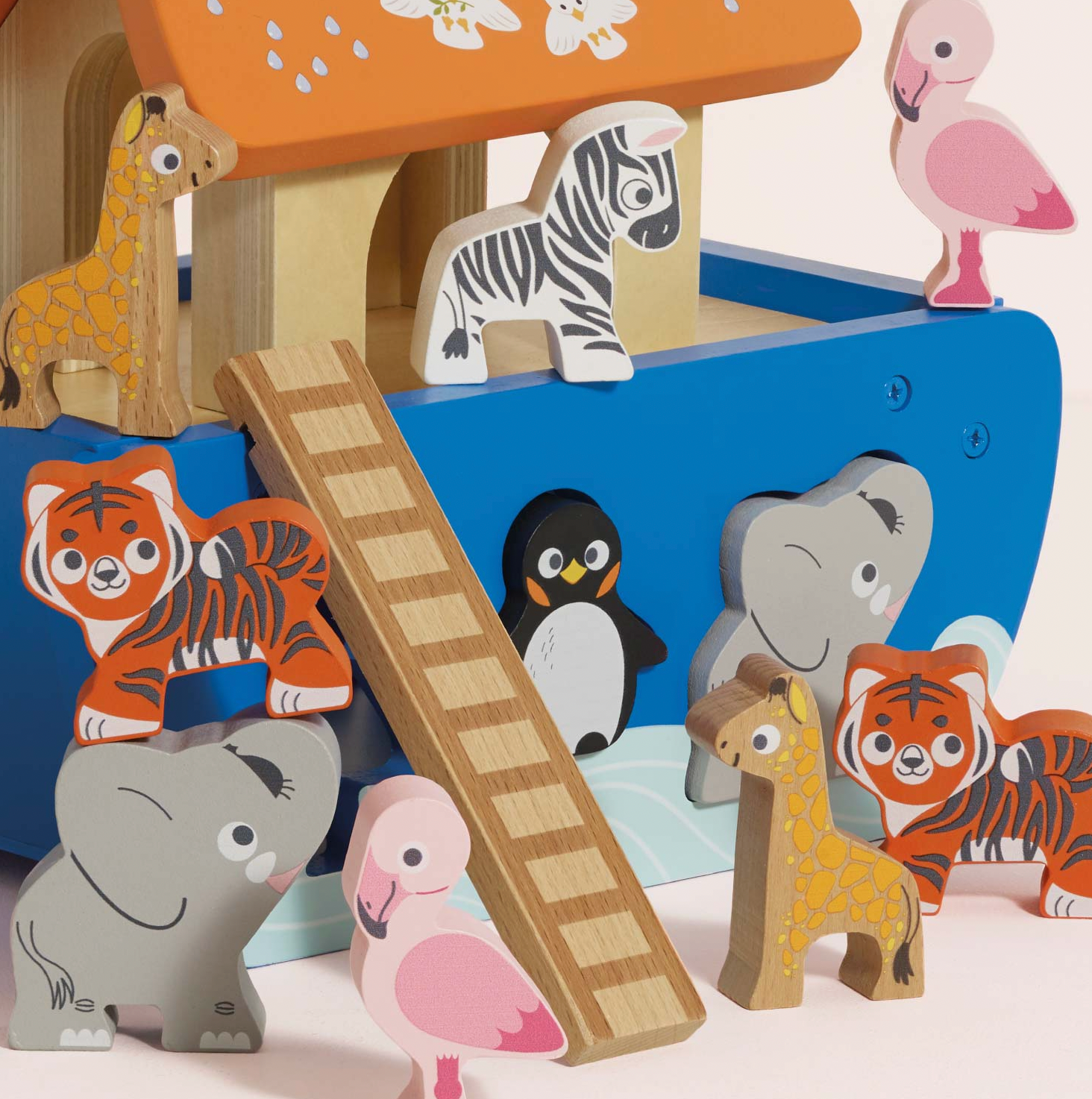 A colorful wooden animal puzzle toy set featuring various animal shapes including a giraffe, zebra, penguin, elephant, tiger, flamingo, and a ladder, arranged on and around a blue boat.