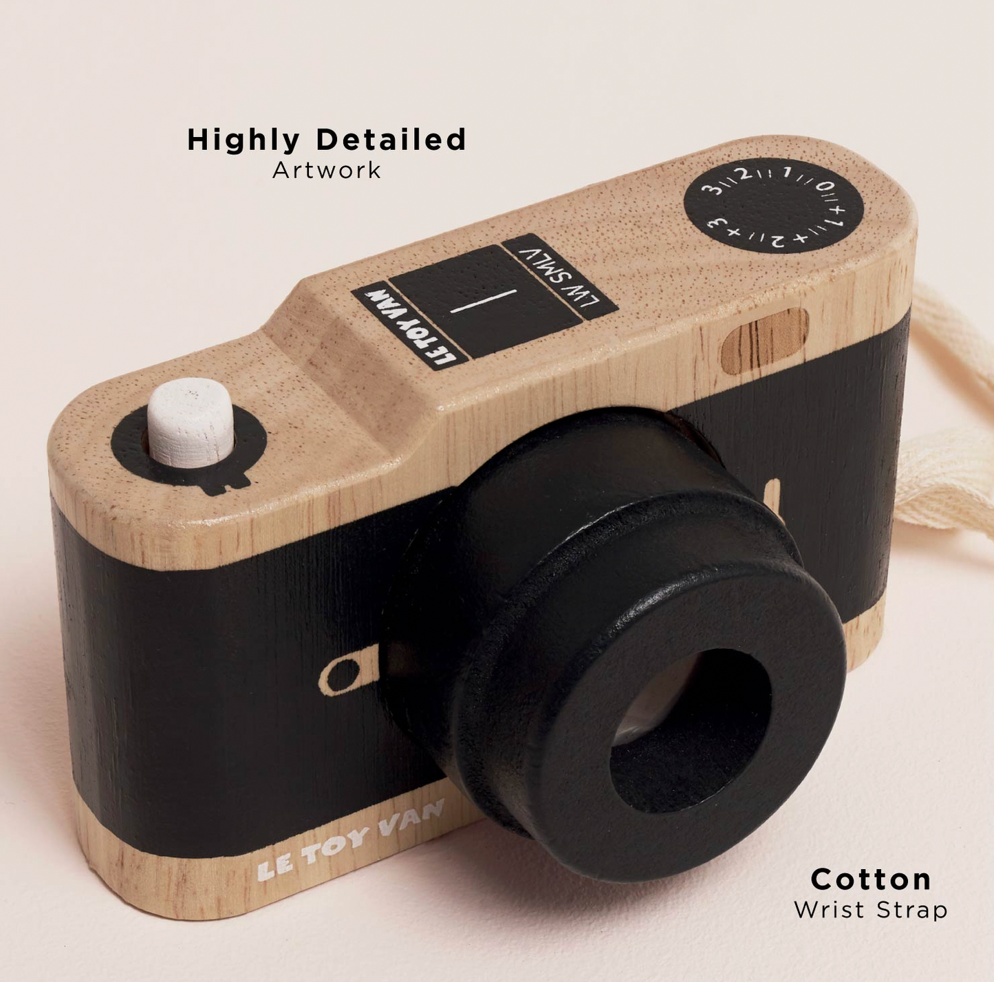 A wooden toy camera with a light natural wood body and black details, shown on a warm beige background with text overlays reading 'Highly Detailed Artwork' and 'Cotton Wrist Strap'.