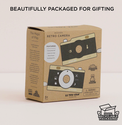LE TOY VAN 'Retro Camera' wooden toy packaging box, featuring a brown kraft cardboard design with illustrations of a wooden camera. The box is shown on a light beige background with promotional text overlays at the top and bottom.