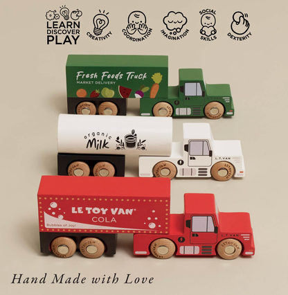 Four wooden toy trucks and trailers arranged on a beige background, with text reading 'LEARN DISCOVER PLAY' at the top and 'Hand Made with Love' at the bottom. The set includes a green market delivery truck, a white milk tanker, a red cola van, and a white tractor, all with natural wood wheels.
