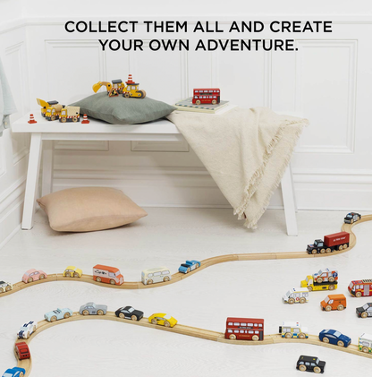 A styled children's room scene with a white bench, pillows, and a cream throw blanket, alongside a wooden toy train track and multiple small toy vehicles on the floor. Large text at the top reads, 'COLLECT THEM ALL AND CREATE YOUR OWN ADVENTURE.