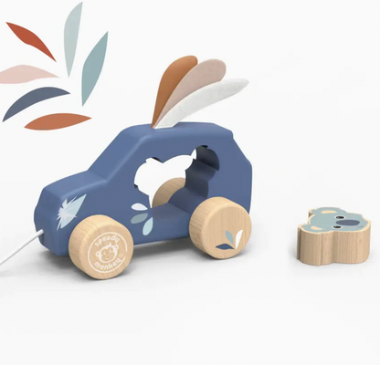 A wooden toy car pull with a blue body, natural wood wheels, and a small matching wooden pull piece on a white background. The brand name 'Peachy Pimlico' is visible on the wheel.