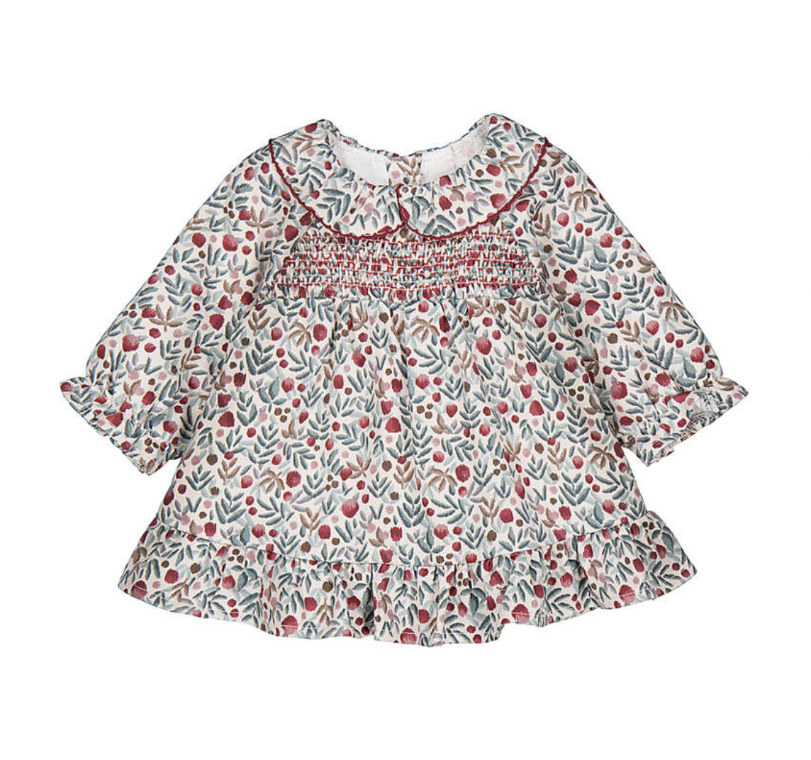 A baby girl's long-sleeve smocked blouse with a delicate red berry and green leaf pattern on an off-white background, featuring a ruffled collar and ruffled hem.