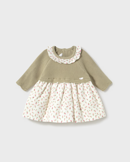 A baby girl's long-sleeve dress with a solid olive green ribbed knit top and a cream-colored skirt covered in a small pink and green floral print, set against a light gray background.
