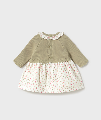 A baby girl's long-sleeve dress with a solid olive green knit top and a white skirt featuring a small pink and green floral print, shown against a light gray background.