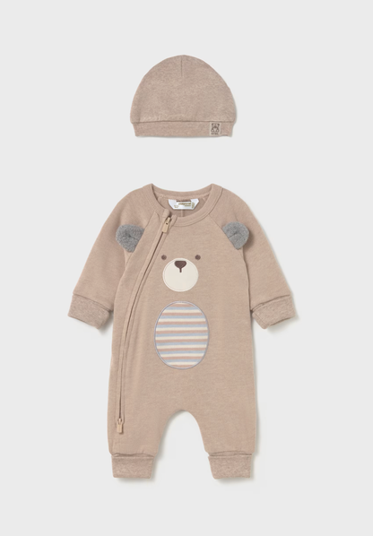 A baby two-piece outfit set consisting of a long-sleeve footless zip-up sleeper and a matching beanie. The sleeper is a light taupe color with a bear face applique on the front featuring gray ears and a striped circular patch on the belly.