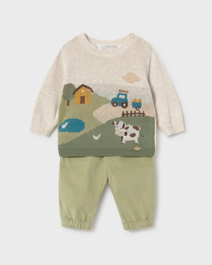 A baby knit two-piece outfit featuring a cream-colored long-sleeve sweater with a colorful farm landscape graphic (including a tractor, barn, pond, and cow) paired with sage green pants with elastic cuffs.