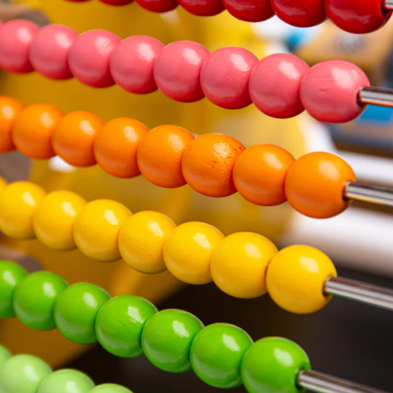Close-up of a colorful wooden abacus with rows of pink, orange, yellow, and green beads on metal rods.