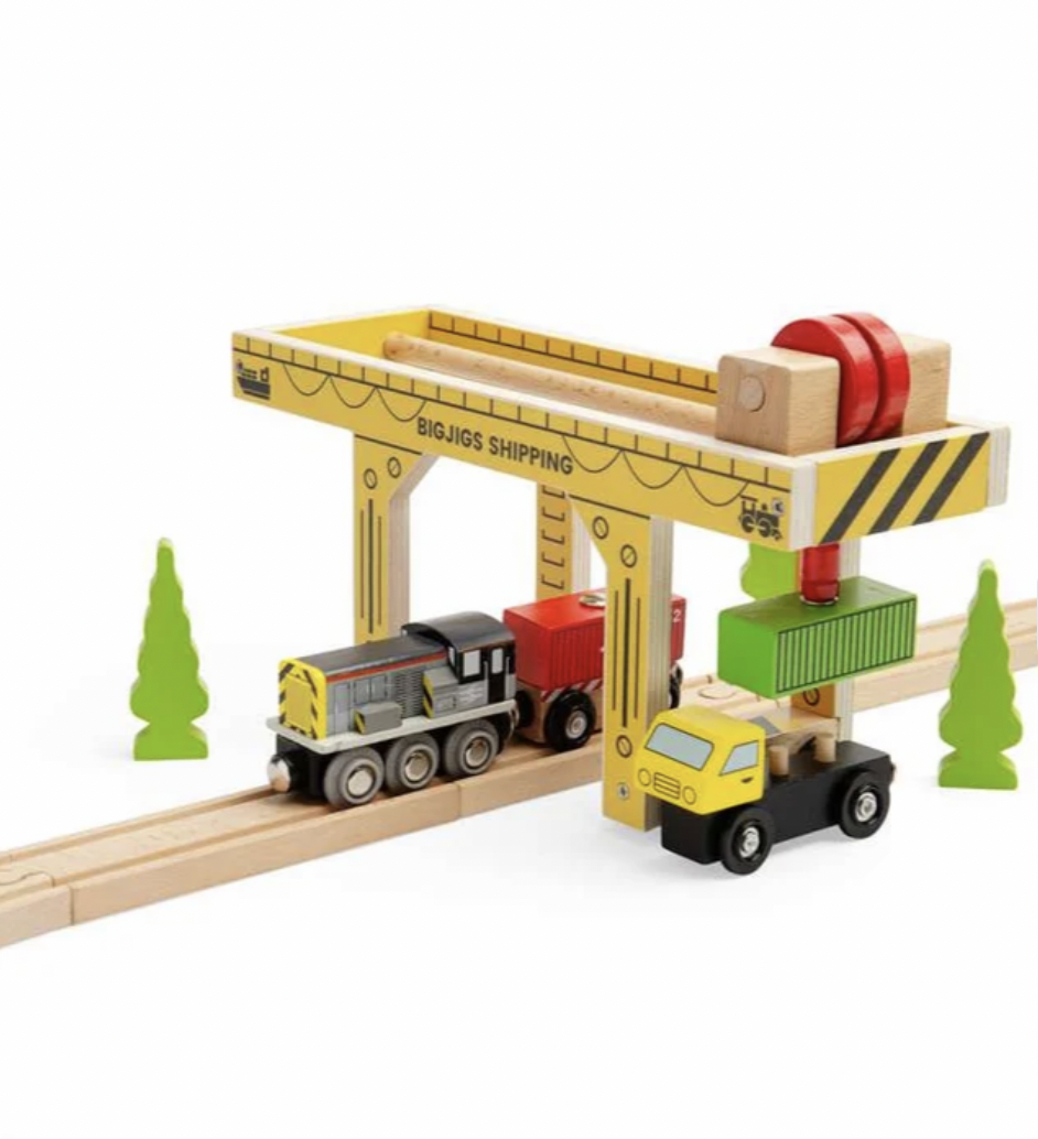 A wooden toy shipping crane set with a yellow and natural wood crane, a red crane hook, and a small yellow and green cargo truck on a white background.