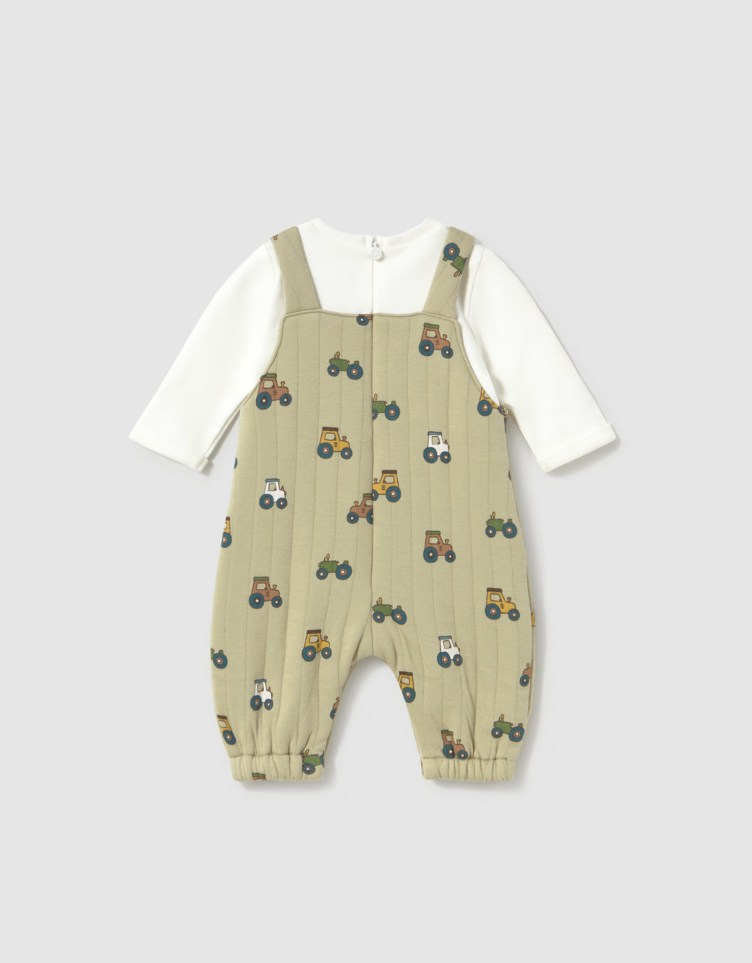 A baby's long-sleeve overall romper featuring a sage green body with a colorful tractor pattern, layered over a white long-sleeve shirt, shown on a neutral gray background.