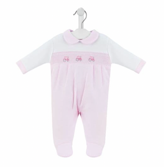 Dandelion smocked tractor baby sleepsuit in pink and white — product shot on white hanger showing white interlock cotton upper with classic flat collar, long white sleeves, pale pink smocked panel with three embroidered pink tractors, pale pink lower body and integrated feet, on white background
