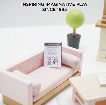 Le Toy Van sitting room dolls house furniture set — close-up lifestyle detail showing the blush pink quilted sofa with bolster cushion and miniature Le Toy Van Post newspaper, with round topiary tree in dark grey pot, "Inspiring Imaginative Play Since 1995" text