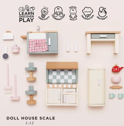 Le Toy Van kitchen dolls house furniture set — flat lay of all 20 pieces with "Doll House Scale 1:12" label and play skills icons for creativity, coordination, social skills, imagination and dexterity; showing sink unit, cooker, fridge, kitchen island, bar stools, red polka-dot kettle, pink mixing bowl, rolling pin, sage green mugs and pink mop set