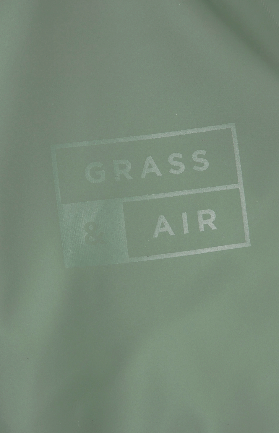 Grass & Air children's waterproof puddle suit in muted sage khaki green — lifestyle image of a child wearing the puddle suit outdoors