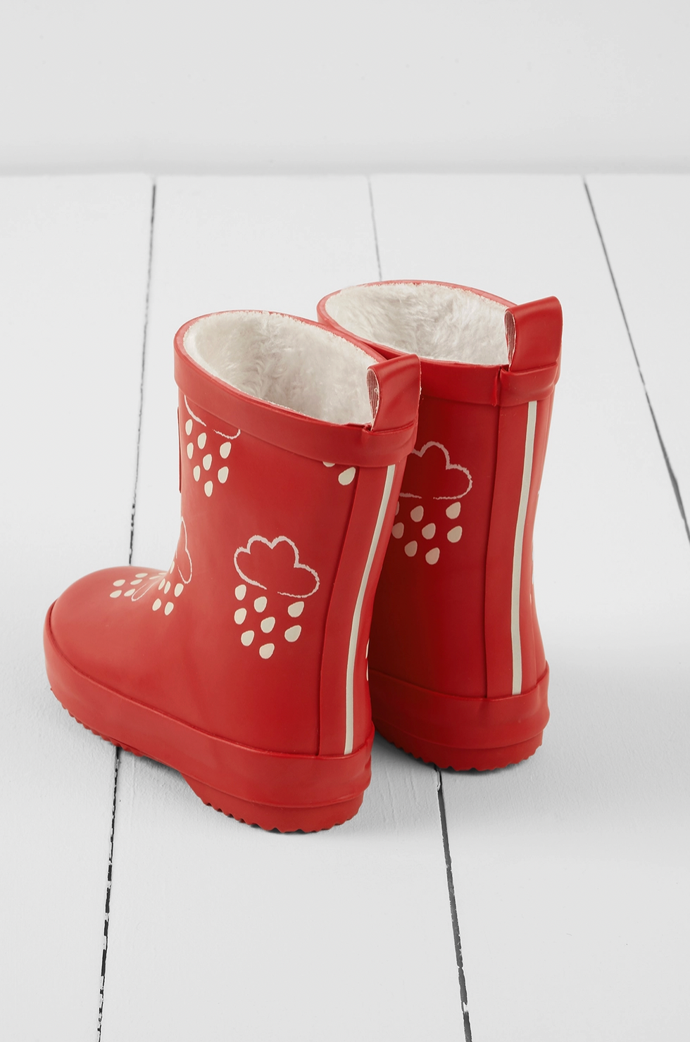 Grass & Air children's ruby red colour-changing wellies — back view showing two pull-on loops, reflective strip running up the back seam for low-light visibility, and cream cloud-and-raindrop motifs on the ruby red rubber