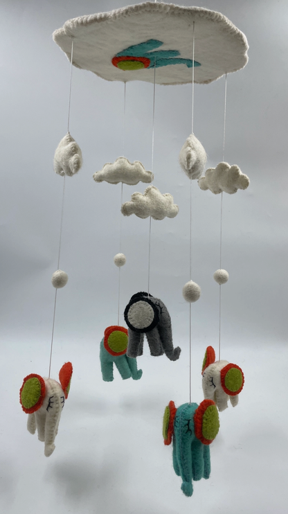 Funky Yak handmade needle-felted elephant nursery cot mobile — side view showing the staggered heights of the five elephants (teal and charcoal grey) with red, orange and lime green circular ear decorations, white felt clouds and pom-pom spacers on fine silver wire