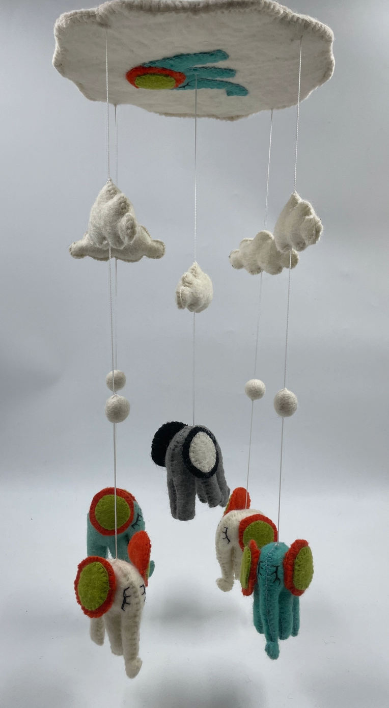 Funky Yak handmade needle-felted elephant nursery cot mobile — close-up detail of three of the five elephants showing the needle-felted teal and charcoal grey bodies with bold red, orange and lime green circular ear decorations and hand-stitched facial details