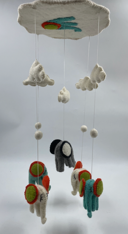 Funky Yak handmade needle-felted elephant nursery cot mobile — close-up detail of three of the five elephants showing the needle-felted teal and charcoal grey bodies with bold red, orange and lime green circular ear decorations and hand-stitched facial details