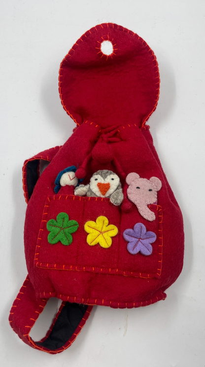 Funky Yak handmade red wool felt finger puppet backpack — open flap view showing the front pocket with three felt finger puppets (blue bird, penguin and pink elephant) peeking out, three appliquéd felt flowers in green, yellow and lavender, and navy-lined padded backpack straps